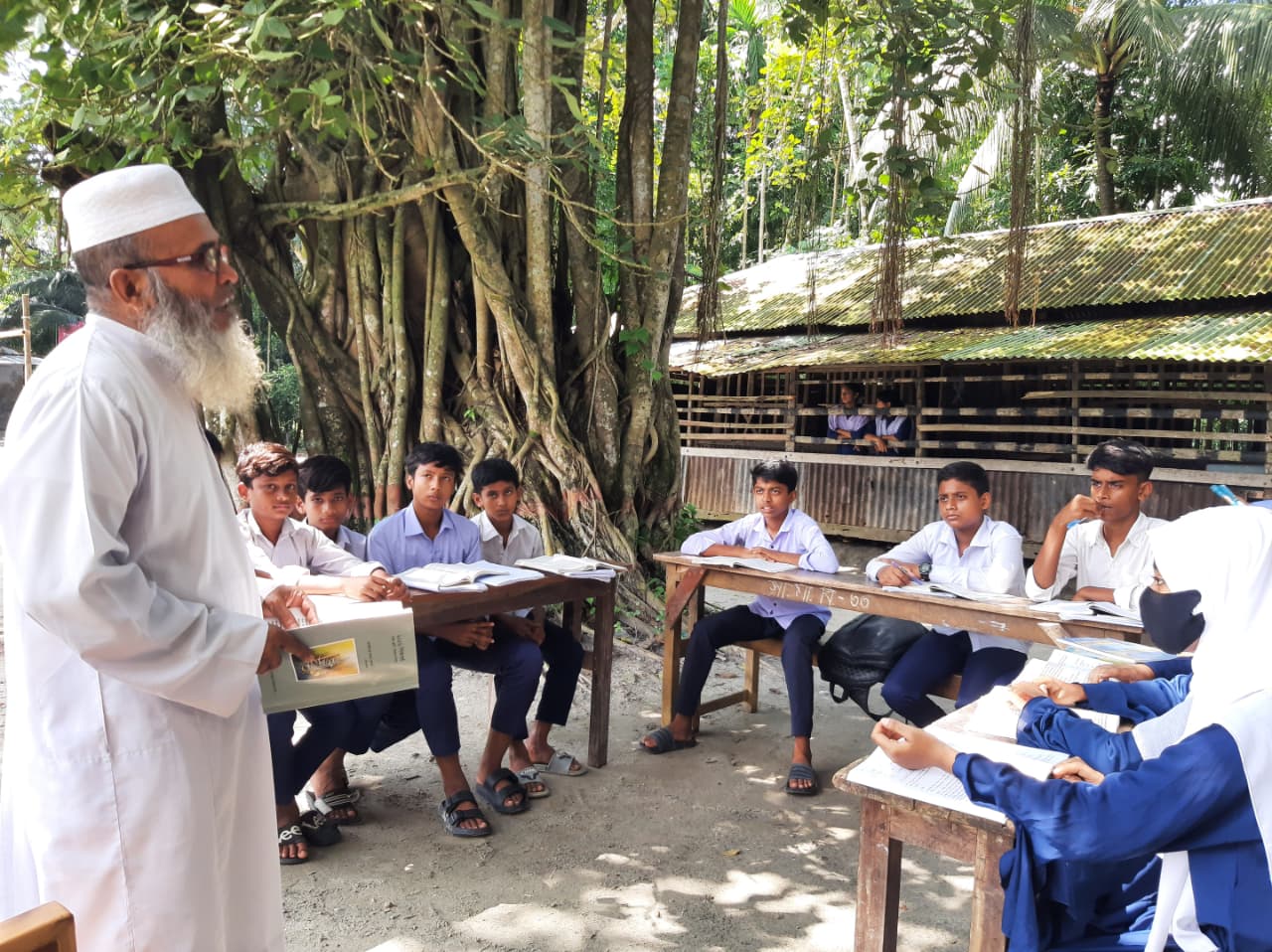 চিতলমারীর সাবোখালী মাধ্যমিক বিদ্যালয়ে শ্রেণিকক্ষ সংকটে বটতলায় ক্লাস করছে শিক্ষার্থীরা